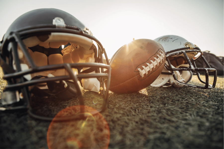 Sporttrade CEO Alex Kane calls for betting regulation overhaul in open letter. American football helmets and ball on a field.