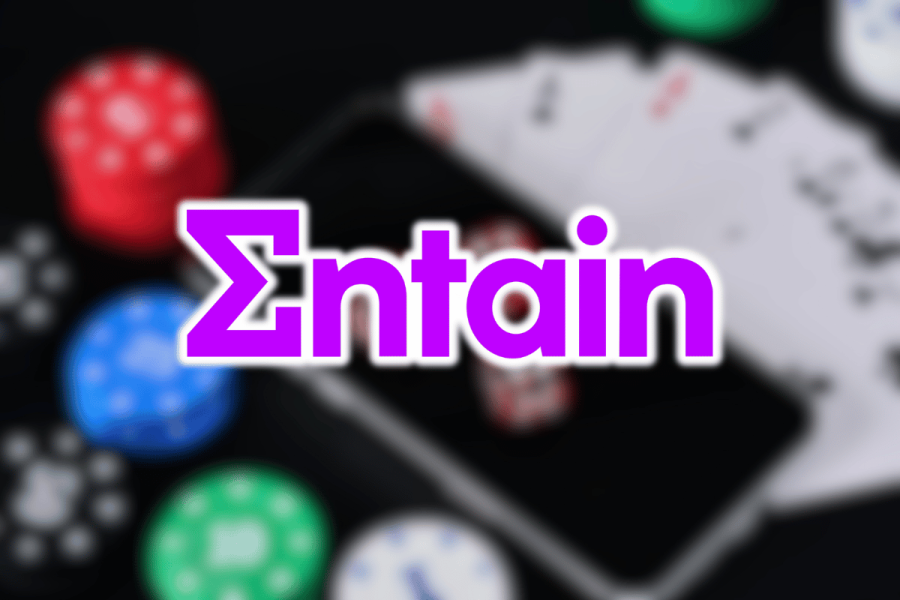 AUSTRAC accuses Entain of failing to stop $152M in suspicious gambling activity. Entain purple logo on top of blurred image of smartphone and gambling memorabilia
