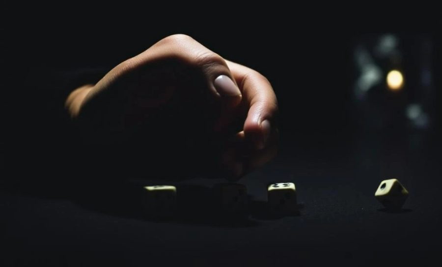 A hand in a dark room over dice