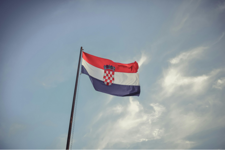 The Republic of Croatia's flag billows in front of a blue sky