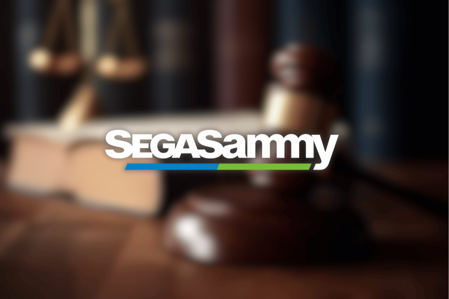 Dutch court orders Sega Sammy to complete $148M Stakelogic acquisition deal. SegaSammy white typography logo on top of blurred image of gavel.
