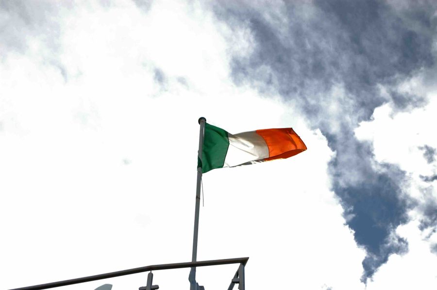 Irish flag flying in the wind. Dark gloomy sky behind it.