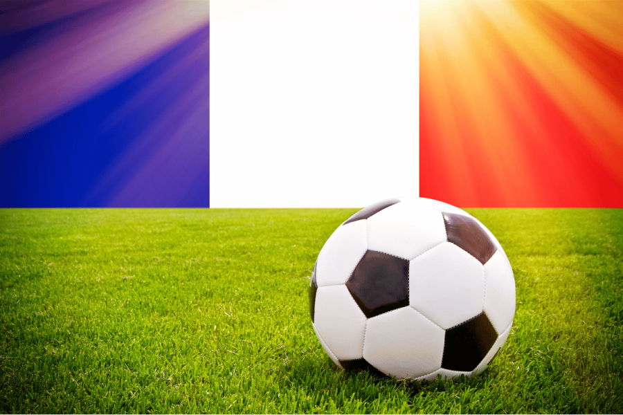 Lotteries and France's top soccer leagues join forces to strengthen French football integrity. Soccer ball on grass in front of red, white, and blue French flag.