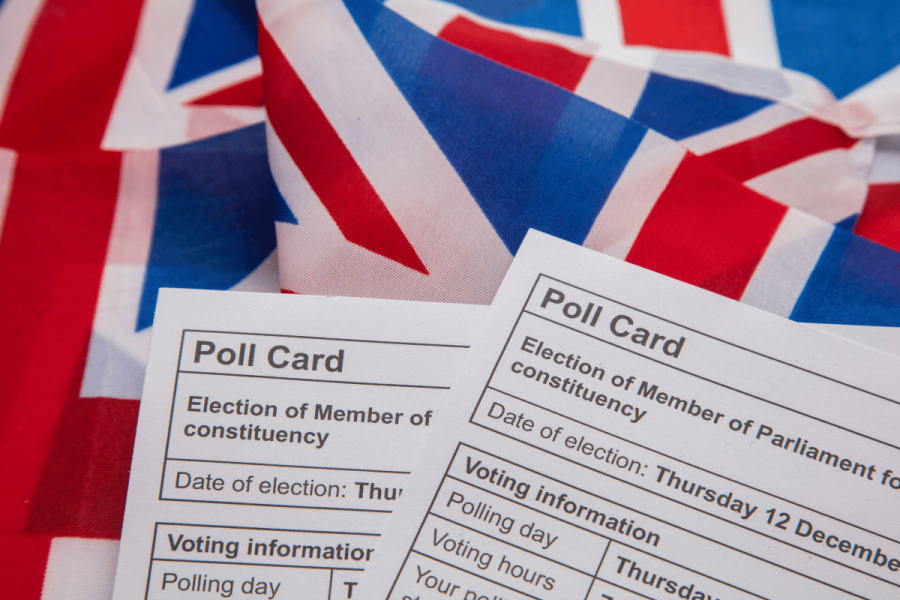 UK's Gambling Commission charges 15 over 2024 General Election betting scandal. Polling cards on top of of red, blue, and white Union Jack flag.