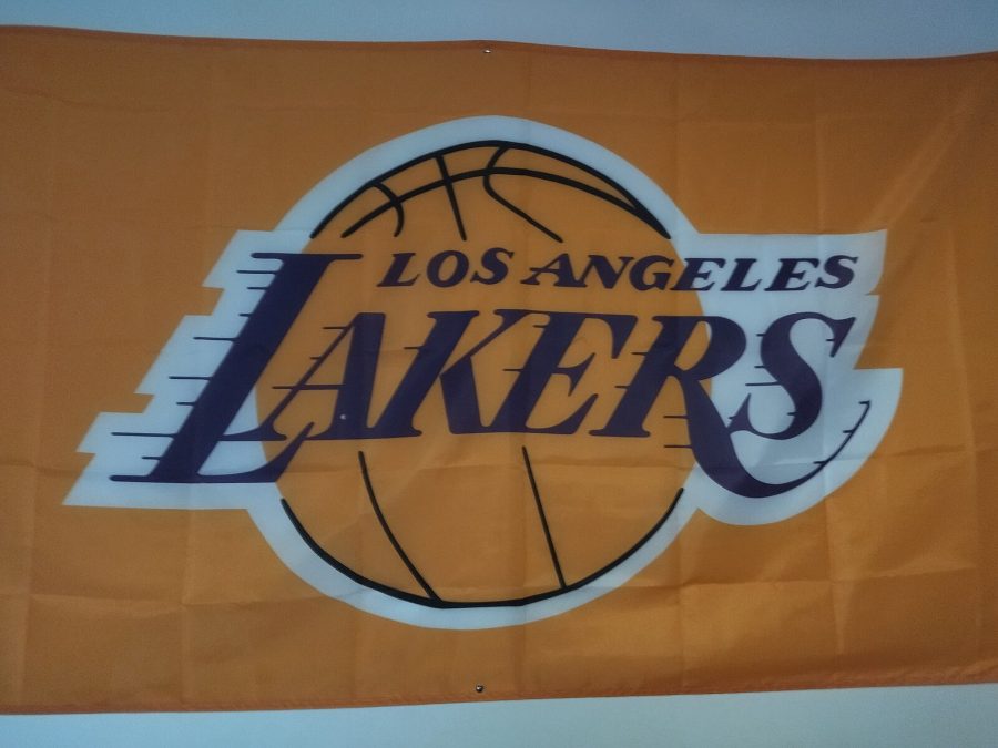 Los Angeles Lakers sign on a banner, orange background, basketball in the center. Sports logo is royal purple.