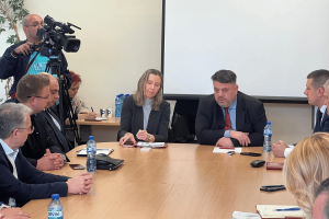 Bulgaria eyes Eurozone to curb grey economy and illegal gambling. A group of officials and experts sit around a conference table in a formal meeting room, with a camera crew recording the discussion; bottled water, notebooks, and microphones are visible on the table.