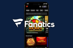 Fanatics Casino app launches in four states with $2M FanCash drop. Smartphone displaying the Fanatics Casino app interface, featuring slot games and navigation buttons, with the Fanatics logo prominently overlaid on a dark blue background.