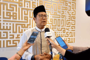 Indonesia’s Islamic leaders strongly reject proposal legalizing casinos for revenue. Cholil Nafis speaks to reporters while wearing a black, traditional hat and striped waistcoat on top of white shirt.