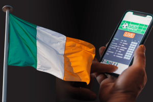 Ireland’s gambling reforms delayed until 2026 despite new regulatory authority. Irish flag next to person betting on smartphone. GRAI considers tiered fees and longer licenses after industry consultation