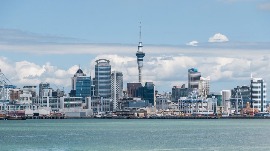 The Skyline of Auckland as seen from Devonport, located at the North Shore. Blue water in the forefornt, buildings in the background. Blue sky.