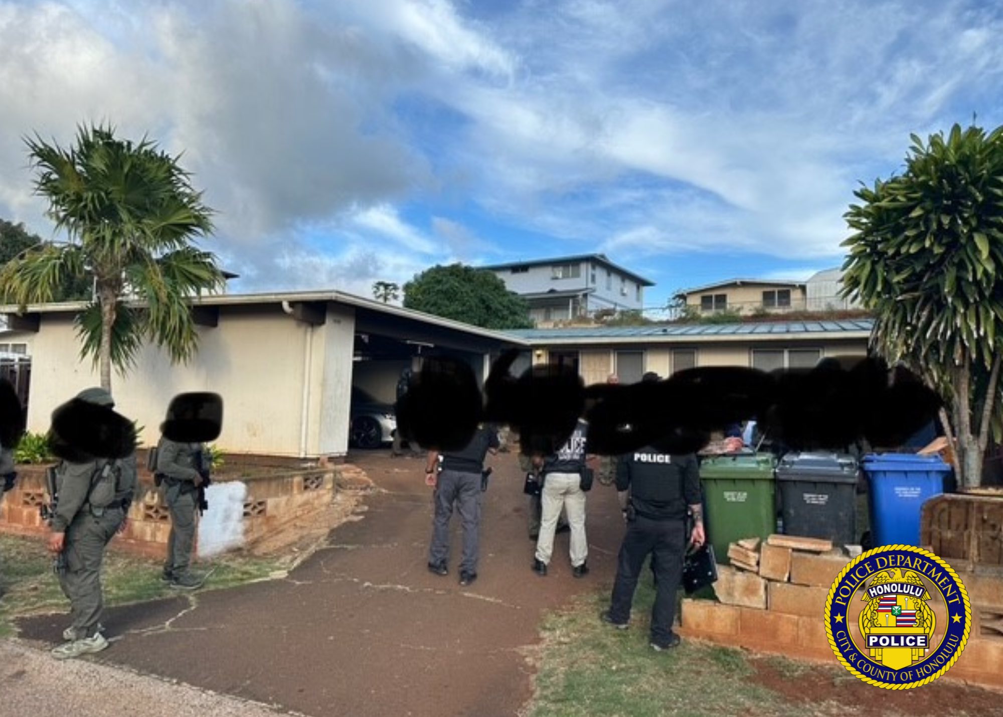 Honolulu Police Department launches raid against illegal gambling den. Group of police officers with faces obscured in front of property 