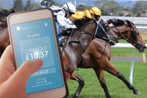 Majority of UK gamblers would flee to black market if taxes rise - BGC survey. Person using a mobile phone to cash out a sports bet during a live horse race, with two jockeys racing neck and neck in the background.