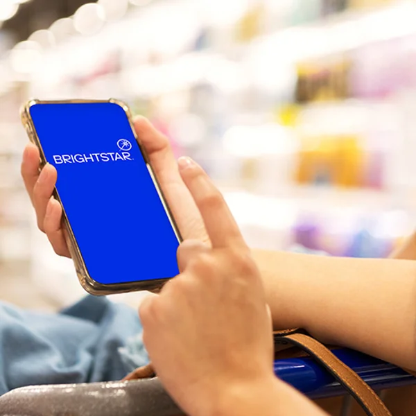 Close up of two hands holding a phone with a blue screen saying 'Brightstar.'