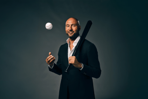 Derek Giter joins the Betmgm Ambassador's list. Derek Giter in a dark suit that carries a black pisser and throw the baseball game, stands against a dark background.