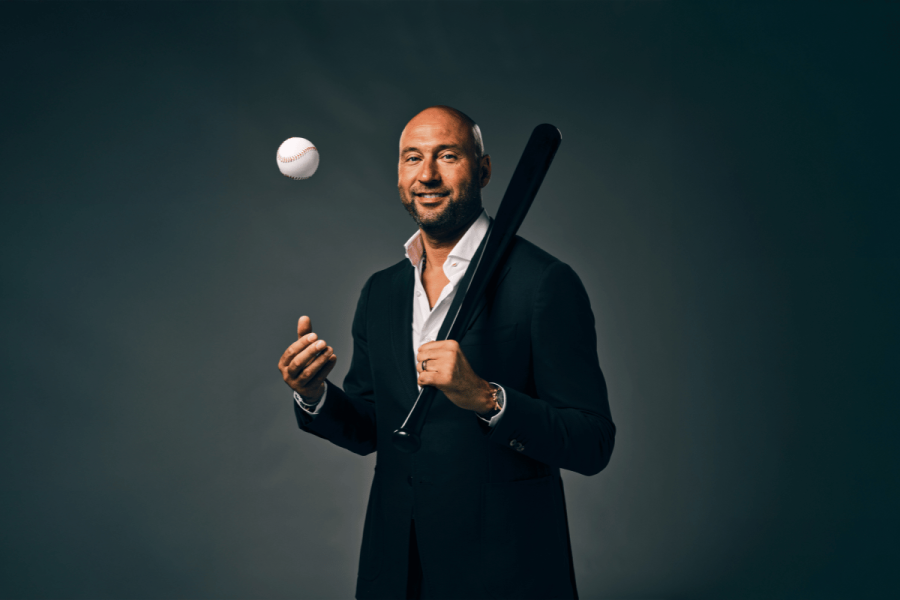 Derek Jeter joins the BetMGM ambassador list. Derek Jeter in a dark suit holding a black baseball bat and tossing a baseball, standing against a dark background.