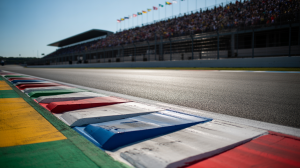 A photo takes a close view of the Formula 1 track, a vibrant show "Michelin" Tire signs. The surface of the asphalt sparkled under bright sunlight, and reveals complex patterns of weariness from the high -speed race. In the unclear background, a section of the runway is visible, muffled with colorful race flags waving in the wind. The lighting is sharp and direct, which highlights the strength and details of the path surface.