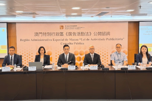 Macau reviews ads law, as it seeks public input on casino promotions. Six officials sit at a conference table during Macau’s public consultation on advertising law amendments, with a banner behind them displaying the event title in Chinese and Portuguese.