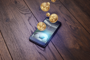 Readybet violates the laws of gambling by correspondingly to users via Betstop. The smartphone displays football with gold coins in the dollar emerging from the screen, and symbolizes the sports betting online and gambling applications.