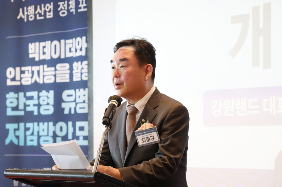 Man stood on stage wearing a suit and speaking into a microphone, with a banner behind him which is written in Korean. Kangwon Land co-hosts an addiction prevention forum in South Korea