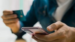 Person holding mobile phone with bank card