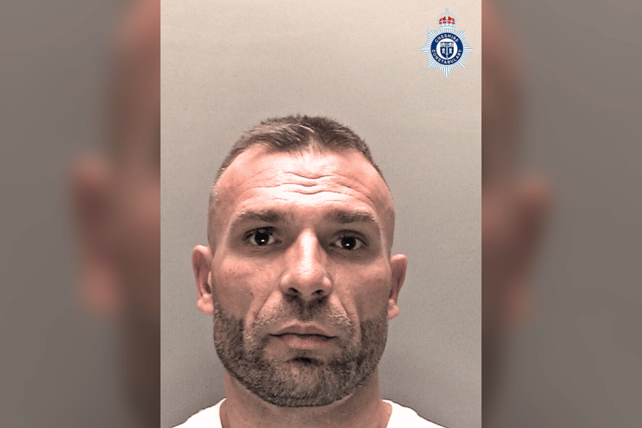 Police mugshot of a man with short hair and a trimmed beard, wearing a white top, taken against a plain background. The Cheshire Constabulary badge is visible in the top-right corner. Man jailed for eight months following casino attack
