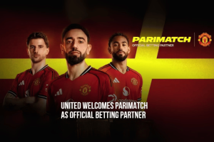 Manchester United players stand in red houses in front of a red and yellow background with the Manchester United logo and the Parimatch logo. The text reads: 