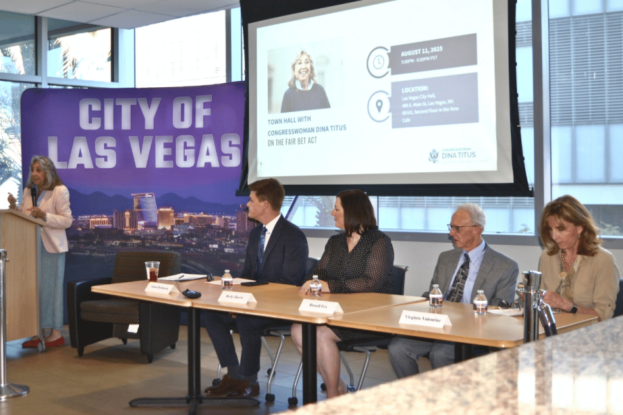 Nevada experts warn federal tax change could harm gambling industry. Congresswoman Dina Titus speaks at a podium during a town hall on the FAIR BET Act at Las Vegas City Hall, with a panel of four experts seated beside her, including Adam Robinson, Becky Harris, Russell Fox, and Virginia Valentine. A large "City of Las Vegas" backdrop and a projected presentation slide are visible behind them.