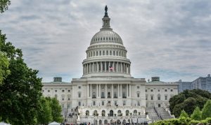 The Senate takes steps to address gambling in the US military. Watch the Capitol Building in the United States in Washington, DC of the forefront with an American flag that flies, under a cloudy sky.