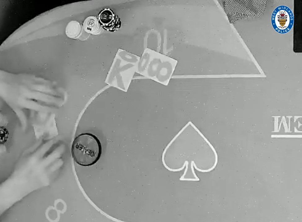 Black and white image of a poker table showing playing cards, poker chips, and a dealer button, released by West Midlands Police.