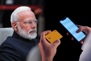 Modi highlights gaming versus gambling distinction in new Online Gaming Act. Indian Prime Minister Narendra Modi wearing earphones, shown beside hands holding a smartphone and a yellow payment card, symbolizing online gaming and digital payments.