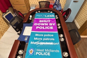 Police intensify crackdown on Birmingham gambling dens amid rising exploitation risks. Poker table in a closed-down gambling den with a large West Midlands Police banner reading “Shut Down By Police.”