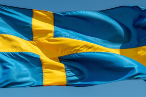 A close-up photograph of the Swedish flag billowing dramatically in a strong breeze against a clear blue sky. Swedish court upholds gambling authority's decision against Kornhults Idrottsklubb