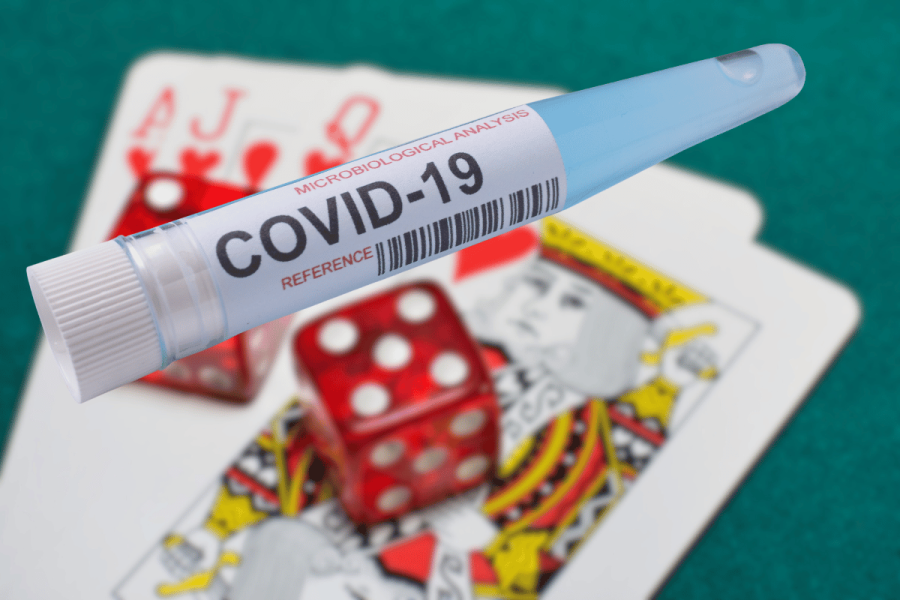 COVID loans fraudster sentenced for using funds on gambling and crypto. A COVID-19 test tube labeled “COVID-19” placed on playing cards and red dice, symbolizing misuse of pandemic relief funds for gambling.