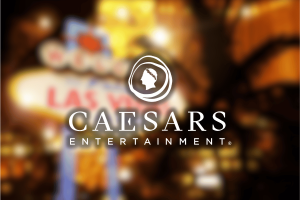 Caesars Entertainment’s third-quarter report posts Las Vegas losses. Caesars Entertainment logo featuring a Roman profile icon and the company name, placed over a blurred Las Vegas Strip background with bright lights.
