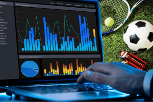 Experts warn prediction markets raise match fixing risks amid NBA sports betting scandal. A person uses a laptop displaying charts and graphs related to sports betting data, with tennis and soccer equipment placed on grass in the background.