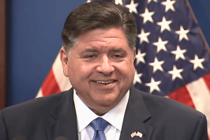 Illinois Gov. Pritzker hits .4M jackpot as gambling tax returns deal winning hand. JB Pritzker smiles in front of US flag