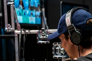SGLA hosts the first online social games exhibition after the G2E committee rejected. A person wearing headphones and a pispul cover runs video equipment while monitoring multiple screens during an online event or live broadcast.