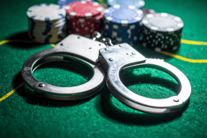 Police arrest 147 in major Selangor gambling syndicate bust. Handcuffs on a poker table with poker chips