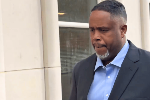 Ex-NBA star Damon Jones pleads not guilty in gambling and poker conspiracy cases. A man in a dark suit and light blue shirt walks outside a building, looking down with a serious expression.