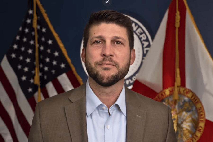 Florida Attorney General wants illegal gambling penalties raised. Attorney General James Uthmeier in a brown blazer and light-colored shirt, stands in front of US and Florida flags