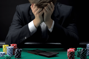 UK unveils first Men's Health Strategy targeting gambling harm nationwide impact. Young devastated businessman losing poker game at casino, gambling addiction
