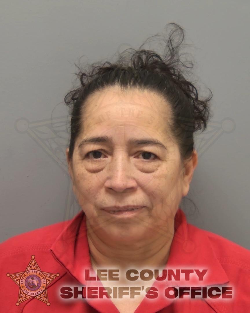 Uma mulher de meia-idade com cabelo escuro e encaracolado puxado para trás olha diretamente para a câmera em uma foto padrão de reserva. Ela está vestindo uma camisa de colarinho vermelho e uma marca d'água fraca do distintivo do Gabinete do Xerife do Condado de Lee aparece atrás dela.