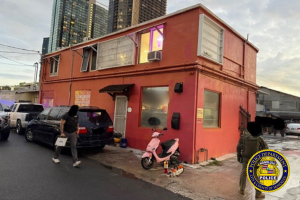 Building in Honolulu, with cars parked outside and a pink scooter. Image shared by police, with Honolulu Police Department badge in the corner. Honolulu police shut down illegal gambling operation, seizing cash and machines