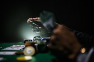 Person holding cash over poker table with chips and playing cards in low light. Are gambling markets becoming entertainment first, betting second?
