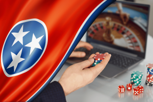 Tennessee Attorney General sends cease-and-desists and warns illegal online sweepstakes casinos. Tennessee state flag beside a person holding casino chips in front of a laptop displaying an online roulette game, symbolizing online gambling enforcement.