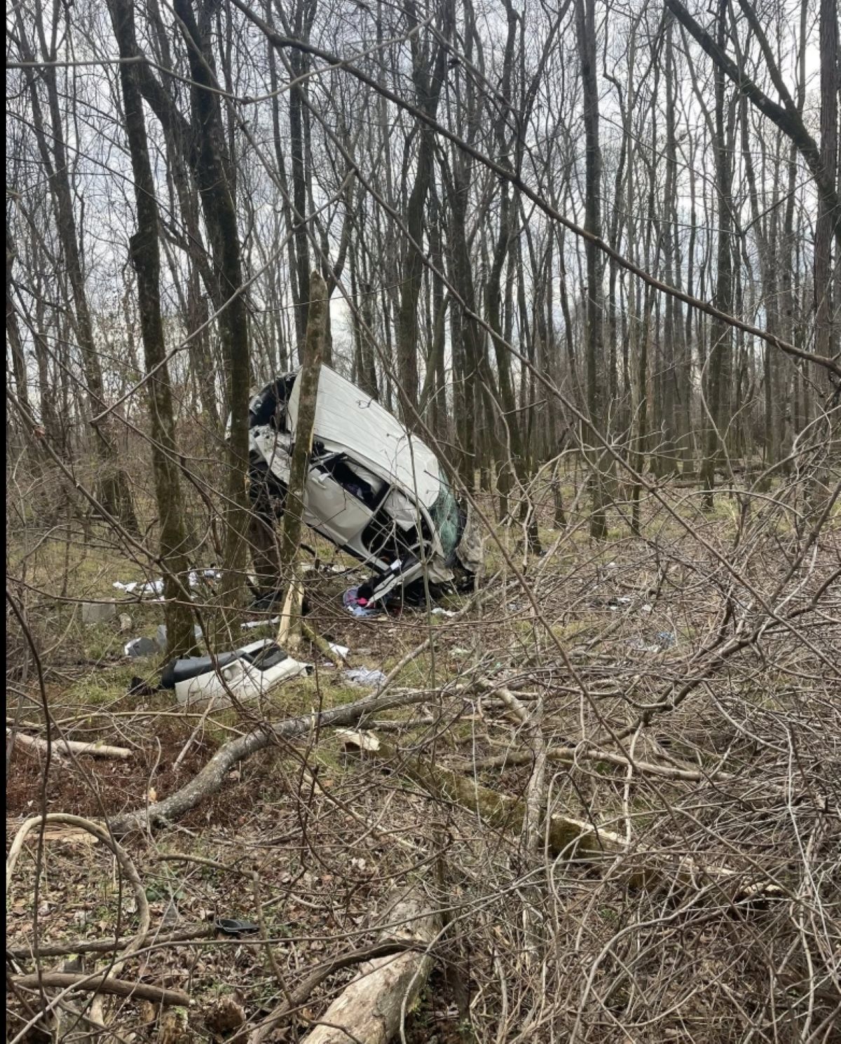 Veículo acidentado encostado em árvores em uma área arborizada após uma perseguição policial no Alabama.