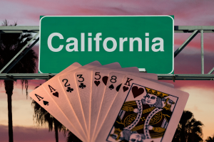 California tribes applaud approval of sweeping new cardroom gambling regulations. Playing cards fanned out in front of a large green California highway sign at sunset, with palm trees silhouetted in the background.