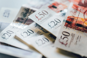 Doncaster woman who stole £300K from partner sentenced for gambling fraud. Close-up of scattered British pound banknotes, including £20 and £50 notes, overlapping on a white surface.