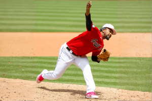 Guardians closer Emmanuel Clase accused of rigging playoff pitch. Baseball pitcher in red Cleveland Guardians shirt throws from mound, right arm extended forward, wearing white pants and bright pink cleats on a sunny field.