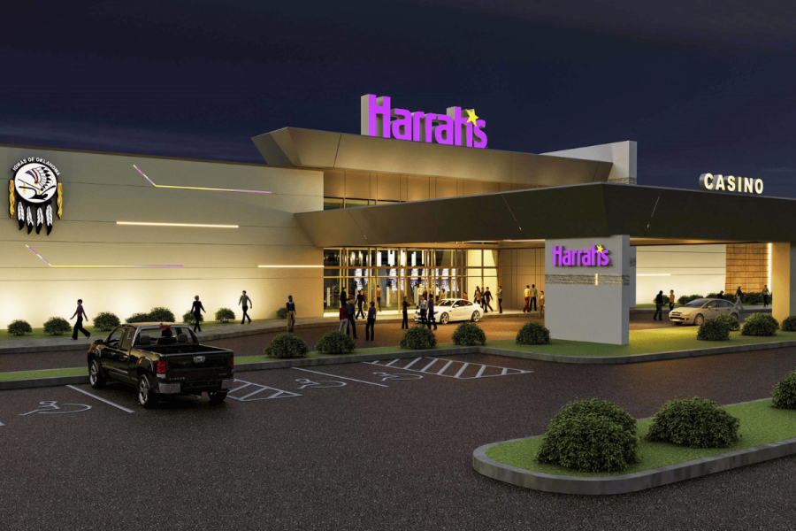 Harrah’s Oklahoma sets April grand opening date with Caesars despite Q4 losses. Harrah’s casino entrance at night with purple illuminated signage, glass doors, parked cars, and visitors crossing a lit driveway and accessible parking.